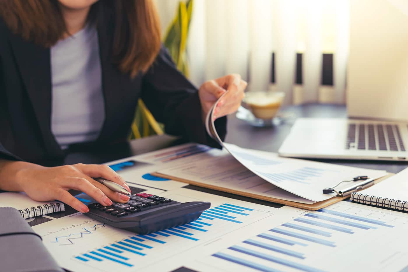 Asesora de una gestoría revisando informes financieros con calculadora y portátil